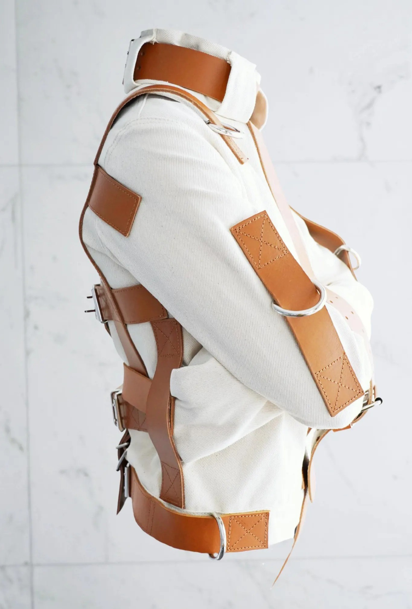 Straightjacket, Restraint jacket, Heavy duty apparel, Technical garment, Structured jacket, Heavy canvas, Cotton duck fabric, Premium leather straps, Genuine cowhide, Metal D-rings, Reinforced stitching, Bespoke tailoring, High-end alternative fashion, Avant-garde apparel, Heavy-duty gear, Cosplay costume, Studio photography prop